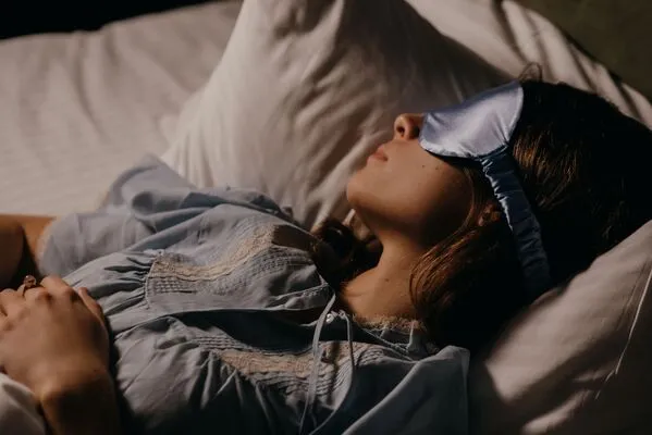 Une femme est allongée dans son lit, un masque sur les yeux pour trouver le sommeil